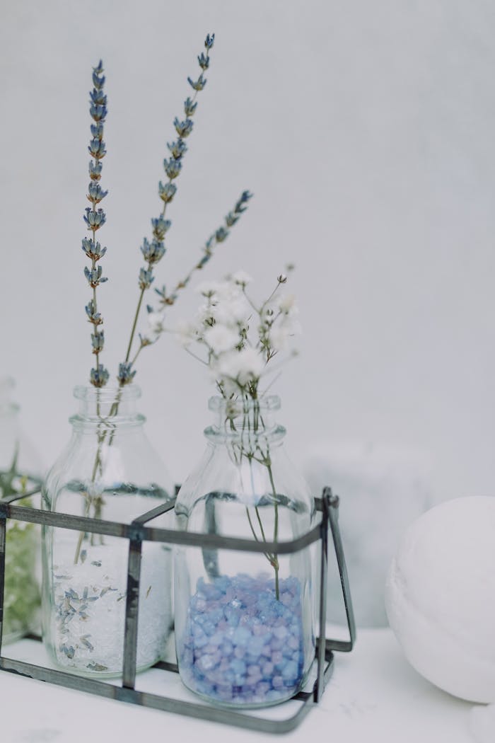Elegant glass bottles with lavender flowers and blue bath salts for a serene spa atmosphere.